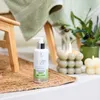A bottle of foot cream is placed on a woven mat next to a lit bubble candle and a small plant. Produktbild-Vorschau