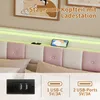 A close-up view of a bed headboard with integrated storage and charging station, showing USB ports and a phone charging. Produktbild-Vorschau