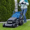 A person is using a cordless lawnmower on a green lawn, with manicured hedges in the background. Produktbild-Vorschau