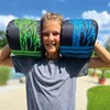 A young person is holding two boxing gloves over their shoulders outdoors. Produktbild-Vorschau