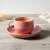 A pink and orange iridescent coffee cup and saucer on a wooden table. Náhled obrázku produktu