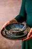 Hands holding a stack of ceramic plates and a bowl. Náhľad obrázku produktu