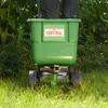 A person is using a green spreader in a grassy area with bushes in the background. Anteprima dell’immagine prodotto