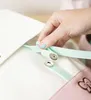 A hand is shown attaching a mint green strap with a snap closure to a white bag. A pink accessory with a bow is visible in the lower right corner. Anteprima dell’immagine prodotto