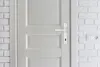 A close-up view of a white door with a white door handle and lock mechanism, set against a white brick wall. Anteprima dell’immagine prodotto