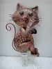 A decorative metal cat figurine mounted on a light gray wall. Produktbild-Vorschau