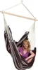 A woman is sitting in a striped hammock chair. Produktbild-Vorschau