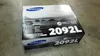 A Samsung toner cartridge box is placed on a concrete floor. Produktbild-Vorschau