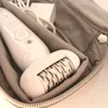 A white epilator is placed inside a gray fabric pouch. Náhľad obrázku produktu