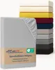 A light gray fitted sheet is shown in the foreground, with a stack of fitted sheets in various colors in the background. Produktbild-Vorschau
