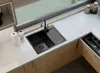 A modern kitchen counter with a black sink and faucet, wooden cabinets, and a window overlooking a garden. Anteprima dell’immagine prodotto