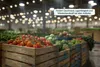 A warehouse or large store interior filled with crates of fresh produce, with overhead lighting. Produktbild-Vorschau