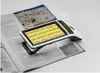 A digital magnifier is placed on an open magazine, with the magnifier's screen displaying enlarged text from the magazine. Anteprima dell’immagine prodotto