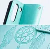 Close-up of a teal book-style phone case with embossed dreamcatcher and feather designs. Náhled obrázku produktu