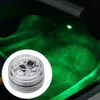 A close-up of a small, clear LED light with internal components, placed on a car floor mat illuminated with green light. Produktbild-Vorschau