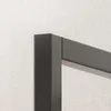 Close-up of a corner of a metal frame, likely part of a shelf or furniture, against a textured white wall. Produktbild-Vorschau