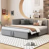 A gray upholstered daybed with an extended pull-out bed, set up in a room with a patterned rug and decorative wall art. Anteprima dell’immagine prodotto