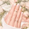 A hand with manicured nails and rings, with a floral background. Podgląd zdjęcia produktu