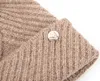 A close-up view of a knitted beige hat with a silver button detail. Produktbild-Vorschau