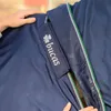 Close-up of a person's hands holding a blue horse blanket with a green and white trim. Produktbild-Vorschau