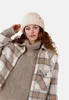 A woman wearing a cream-colored fuzzy hat and a plaid jacket. Produktbild-Vorschau
