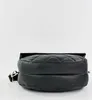 A black quilted handbag is shown from a side angle, resting on a white surface. Anteprima dell’immagine prodotto