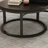 A close-up view of a round coffee table with a dark wood top and black metal legs and base, resting on a grey carpet. Náhľad obrázku produktu