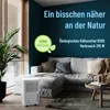 A dehumidifier is placed in a living room setting next to a couch and a window. Produktbild-Vorschau