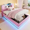 A pink upholstered bed with storage is shown in a bedroom setting, with the storage compartment open and containing luggage. The bed has LED lighting around its base. Produktbild-Vorschau