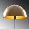 A close-up view of a gold-colored dome-shaped lampshade with a brass interior, mounted on a dark stand. Produktbild-Vorschau