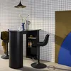 A modern bar table with two bar stools in a room with a tiled wall and abstract wall art. Produktbild-Vorschau