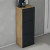 A narrow, tall shoe cabinet with a wood-grain finish on the left and three black cabinet fronts on the right, set against a grey wall and light grey floor, with a doorway visible on the right. Voir les images du produit