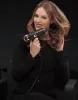 A woman is holding a black and gold hair dryer and styling her hair. Podgląd zdjęcia produktu