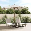 Two lounge chairs and a large umbrella are set up on a patio with lush greenery and a wooden fence in the background. Produktbild-Vorschau