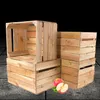 Several wooden crates are stacked, with two apples and leaves in the foreground. Produktbild-Vorschau
