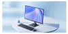 A modern computer monitor, keyboard, and mouse are displayed on a round white table against a soft blue background. Produktbild-Vorschau