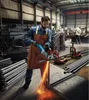 A worker in a factory is using an angle grinder to cut metal pipes. Sparks are flying from the grinder. Podgląd zdjęcia produktu