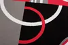 A close-up abstract pattern of a rug with geometric shapes and lines in black, gray, white, and red. Náhľad obrázku produktu