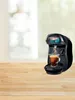 A coffee machine brewing coffee into a clear glass cup on a wooden surface. Voir les images du produit