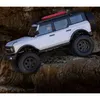A white remote-controlled car is climbing over rocks. Podgląd zdjęcia produktu