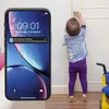 A child is reaching for a doorknob while a smartphone displays a notification about movement detected in the nursery. Produktbild-Vorschau