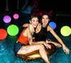 Zwei lachende Frauen in einem Schwimmbad bei Nacht, umgeben von leuchtenden mehrfarbigen LED-Poolleuchten Anteprima dell’immagine prodotto