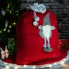 A large red Christmas sack decorated with a gnome and pom-poms, placed next to a decorated Christmas tree and presents. Produktbild-Vorschau