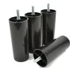 Four black plastic furniture legs with threaded bolts are arranged on a white background. One leg is lying on its side in the foreground, while the other three stand upright behind it. Voir les images du produit