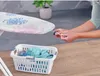 A person is adjusting an ironing board cover over a laundry basket filled with clothes. Produktbild-Vorschau