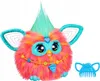 A colorful, fluffy toy with large eyes and teal accents, sitting on a white background. A blue comb accessory is placed to the right of the toy. Podgląd zdjęcia produktu