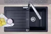 A black kitchen sink with a faucet, drain, and a drying rack area. There are also some lemons and a soap dispenser on the drying rack. Produktbild-Vorschau