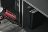 A hand-held vacuum cleaner is cleaning the floor next to a bookshelf. Produktbild-Vorschau