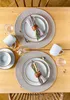 A table setting for two with plates, napkins, mugs, and cutlery. Produktbild-Vorschau