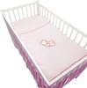A baby crib with pink bedding featuring a teddy bear embroidery. Produktbild-Vorschau